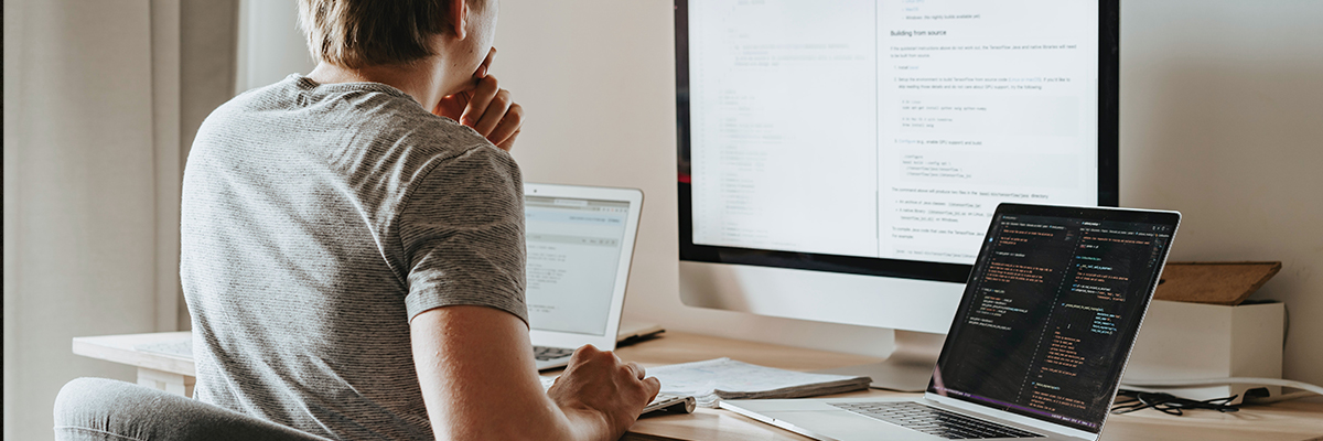 Freelance web developer working on a table with computer and laptop